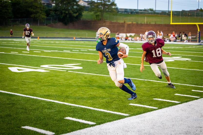 A football player runs down the sideline with the ball